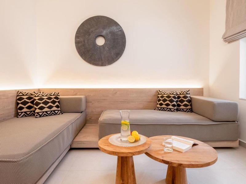 Nowoczesny salon z szarą kanapą narożną, okrągłymi drewnianymi stolikami i dekoracją ścienną.