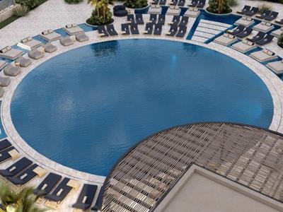 Round hotel pool with lounge chairs and umbrellas on the terrace.
