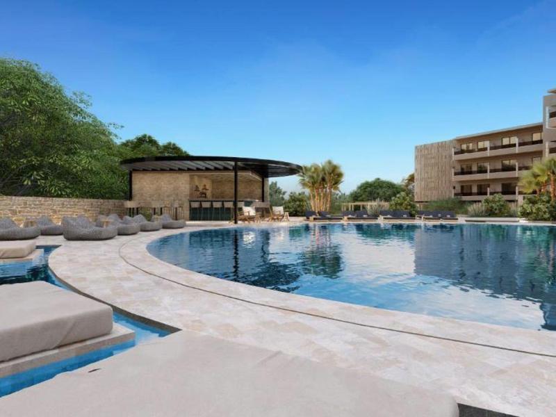 Modern hotel pool with lounge chairs and umbrella under clear blue sky.