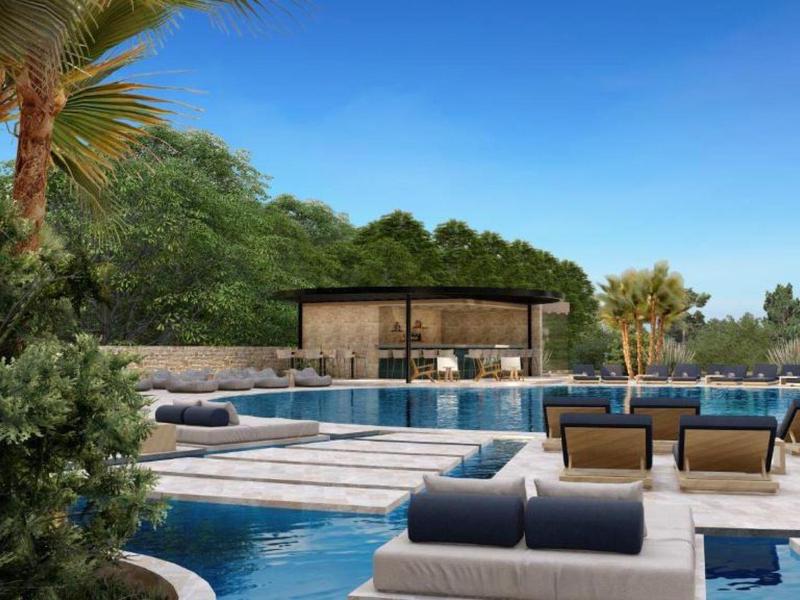 Modern outdoor pool area with seating and a pavilion under a blue sky.