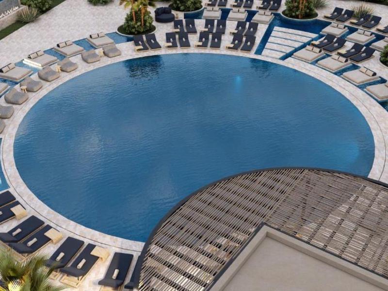 Modern round outdoor pool with sun loungers and plants at a hotel