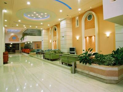 Ampia hall dell'hotel con pareti luminose, piante e comodi posti a sedere.