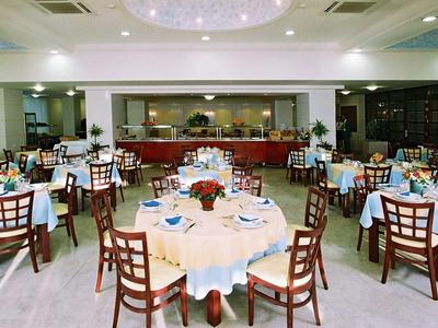 Area ristorante ben illuminata con tavoli rotondi e sedie apparecchiate per gli ospiti.