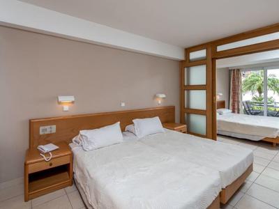 Chambre lumineuse avec deux lits simples et accès à une terrasse donnant sur la piscine.