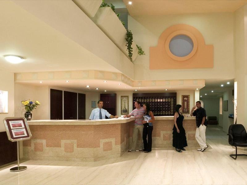 Accueil d'hôtel lumineux avec deux employés assistant les clients.