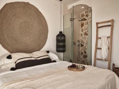 Camera accogliente con tappeto rotondo, doccia moderna e scala decorativa sulla parete.