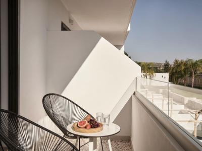 Balcone con due sedie e piccolo tavolo con bevande e frutta in hotel moderno.