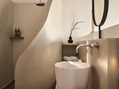 Bagno moderno con lavandino rotondo, rubinetto a parete e arredamento minimalista.