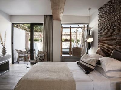 Camera d'hotel moderna con letto matrimoniale e accesso a una terrazza con zona salotto.