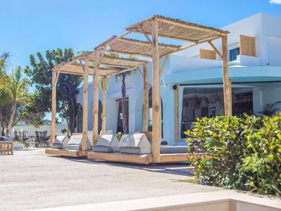 Modern hotel outdoor area with wooden loungers and white cushions under sunshades.