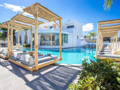 Modern pool area with white covered loungers at a hotel in sunny weather.