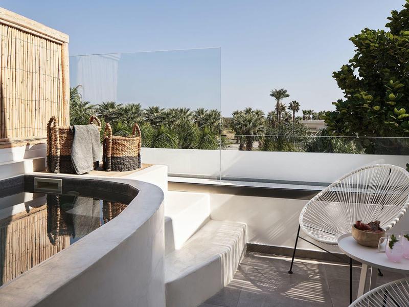 Terrazza soleggiata con area salotto bianca moderna e vista su alberi verdi