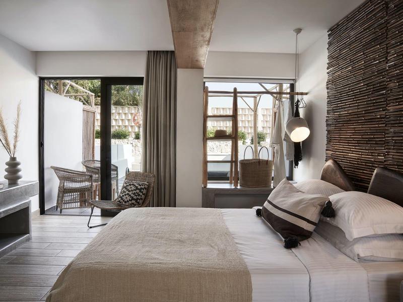 Camera d'hotel moderna con letto matrimoniale e accesso a una terrazza con zona salotto.