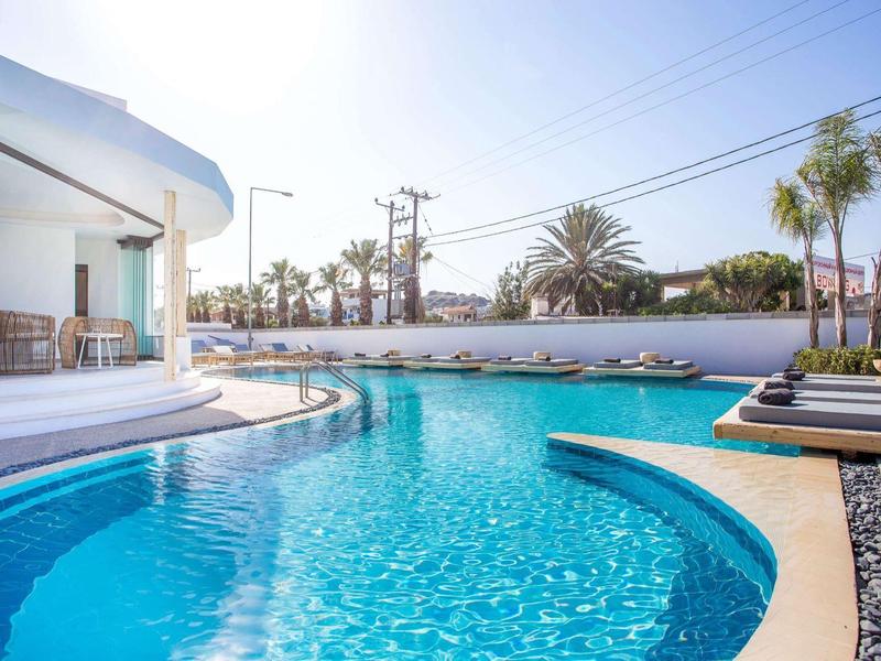 Elegante piscina esterna con lettini e architettura moderna sotto un cielo limpido.