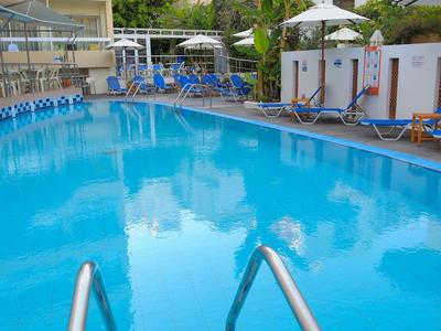 Piscina azul clara con tumbonas y sombrillas en el jardín de un hotel.