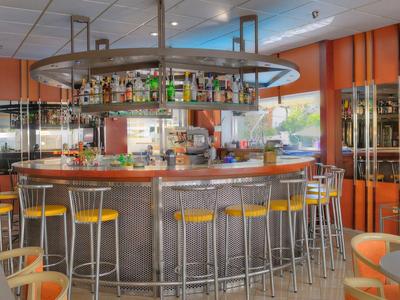 Bar de hotel moderno con taburetes redondos y decoración de pared naranja