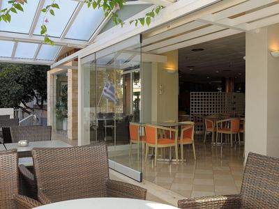 Área de asientos abierta con muebles de mimbre y mesas en un restaurante moderno y luminoso