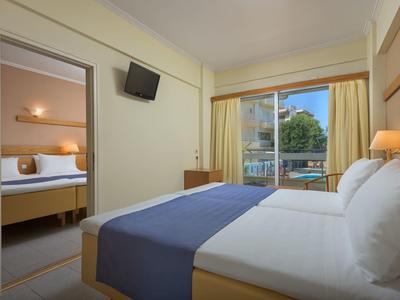 Tweepersoonskamer met balkon deur, tv en aangrenzende slaapkamer.