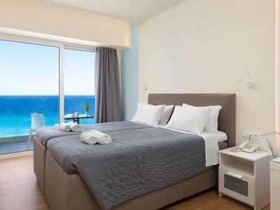 Modern hotelkamer met tweepersoonsbed en zeezicht door grote ramen