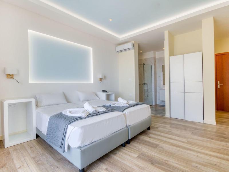 Modern hotelkamer met twee eenpersoonsbedden, minimalistisch ontwerp en lichte houten vloer.