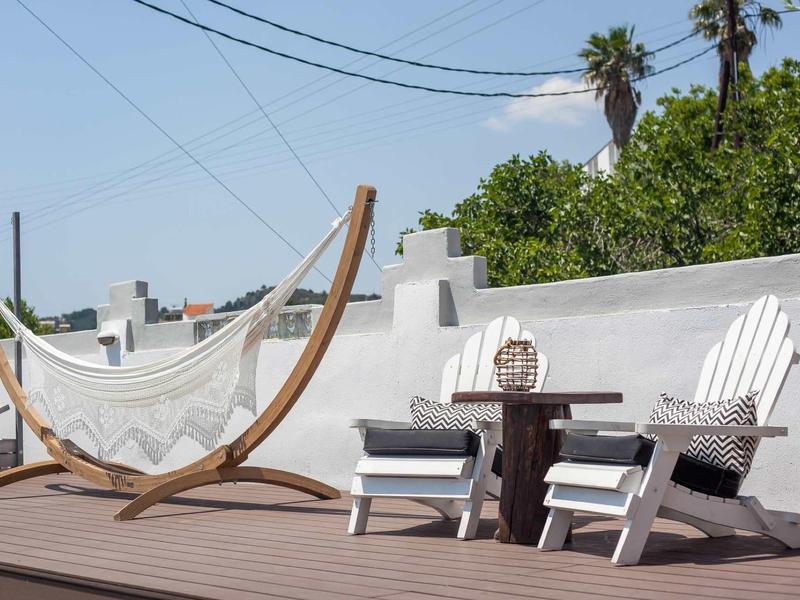 Rooftop terrace with hammock and two chairs next to a small table