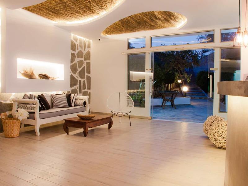 Bright, modern hotel lobby area with stylish wooden furniture and view of the pool at night.