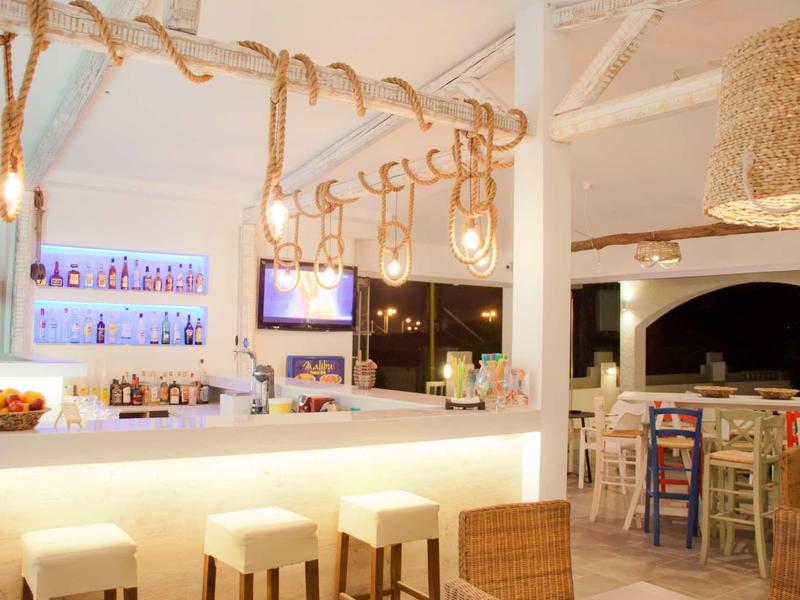 Bright hotel bar area with stools, hanging rings, and cozy seating.