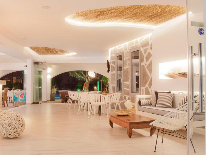Bright hotel lounge area with modern white furniture and warm ceiling lighting.