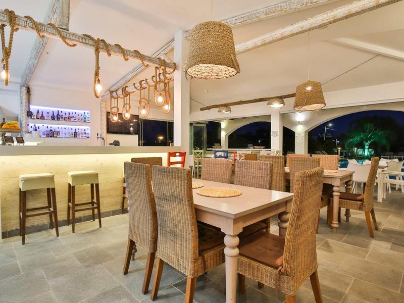 Cozy outdoor bar area with wooden tables, chairs, and warm lighting at a hotel.