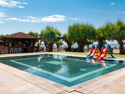 Rechteckiger Pool mit Wasserrutsche, umgeben von Bäumen, Holzhütte und blauem Himmel.
