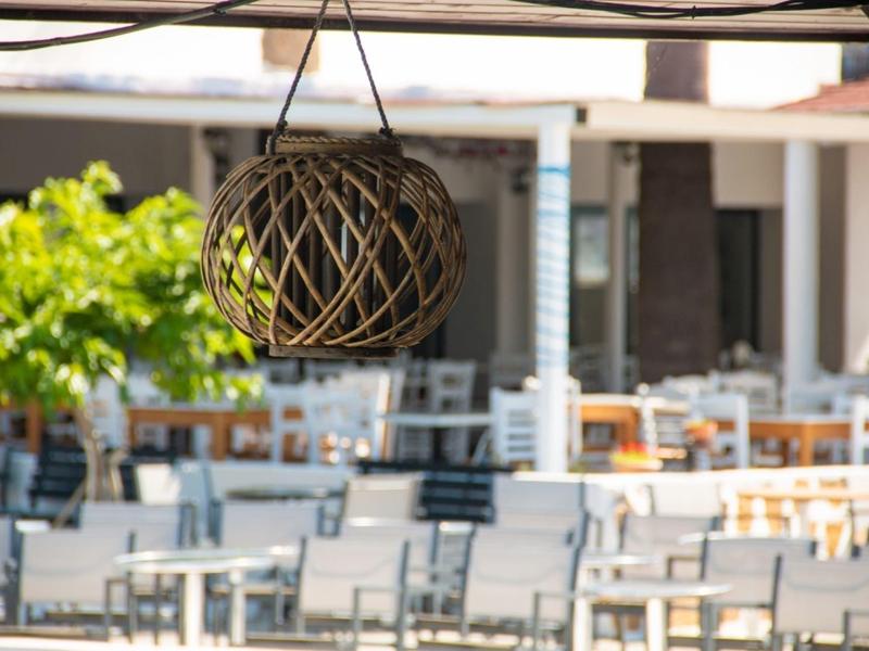 An empty outdoor restaurant patio with a hanging decorative lamp in the foreground