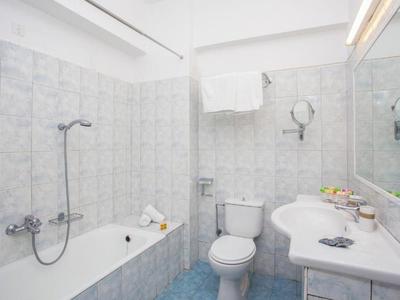 Bagno compatto con vasca da bagno, WC e lavabo in piastrelle chiare.