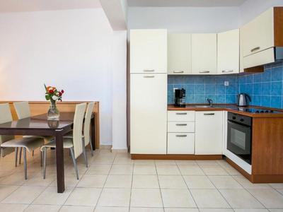 Zona de cocina moderna con salpicadero de azulejos azules y comedor con mesa y sillas.