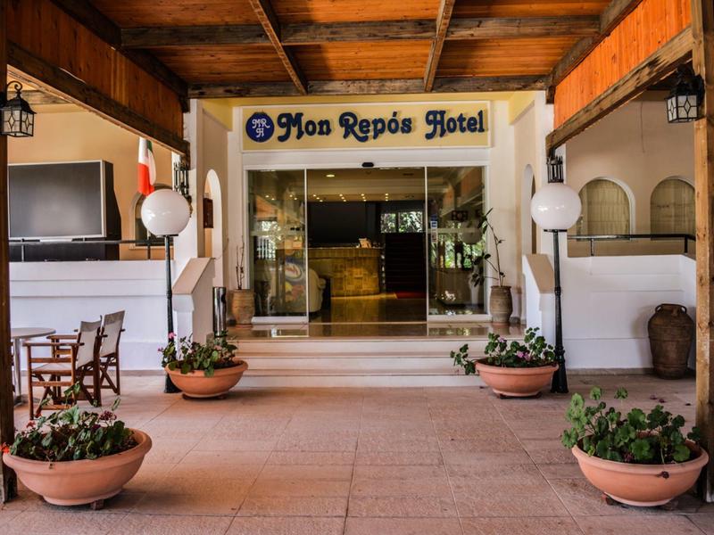 Ingresso dell'hotel con piante e soffitto in legno, insegna 'Mon Repos Hotel' visibile.