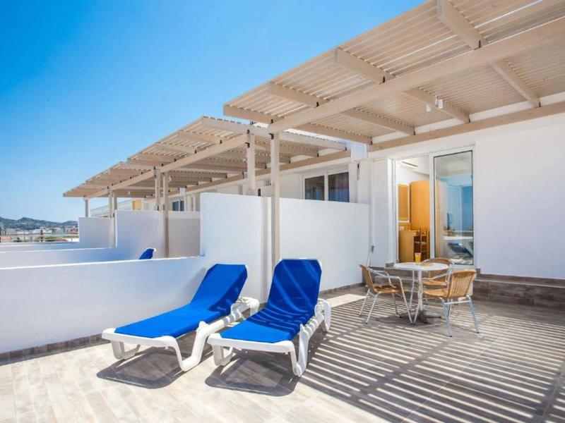 Terrazza con lettini blu e zona pranzo con vista sul mare.