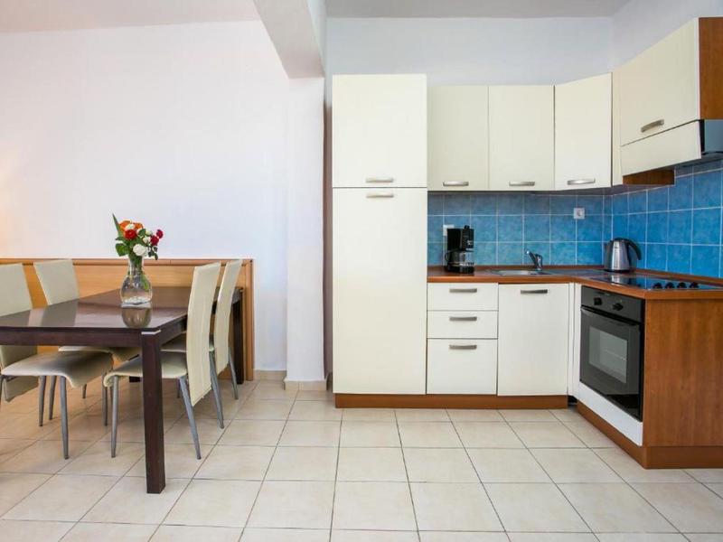 Angolo cottura moderno con piastrelle blu e area pranzo adiacente con tavolo e sedie.