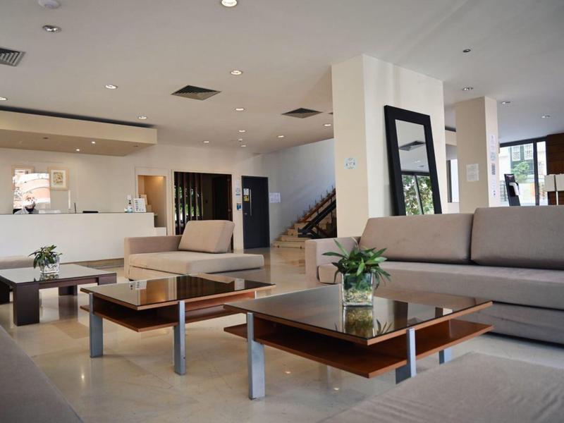 Bright modern hotel lobby area with sofas and coffee tables with plants.