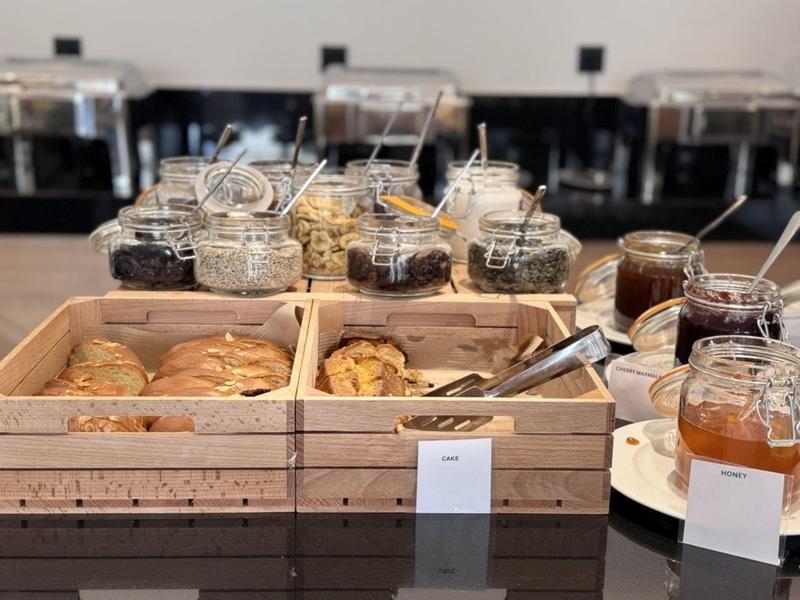 Breakfast buffet with various jams and cookies in wooden boxes.