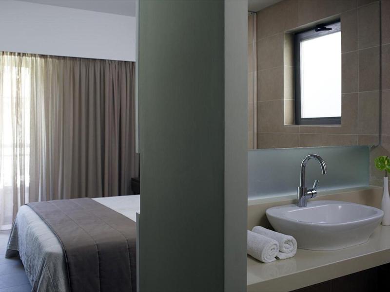 Modern hotel room with bed and bathroom sink with towels.