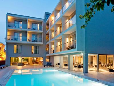 Hotel moderno con piscina illuminata e balconi al crepuscolo.