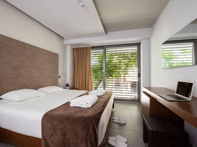 Camera d'hotel moderna con letto matrimoniale, copriletto marrone e scrivania con laptop.