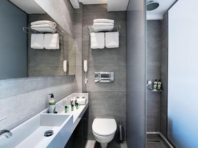 Modern, clean bathroom area with white sink, toilet, and towels on a gray wall.