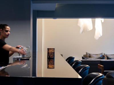 Bartender prepares drinks at a modern hotel bar with seating area.
