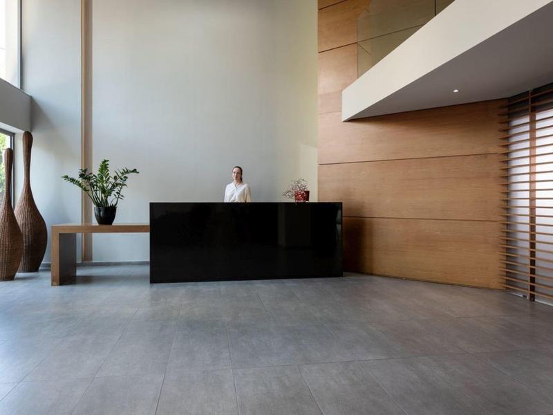 Modern hotel reception area with black desk and wooden wall panels.