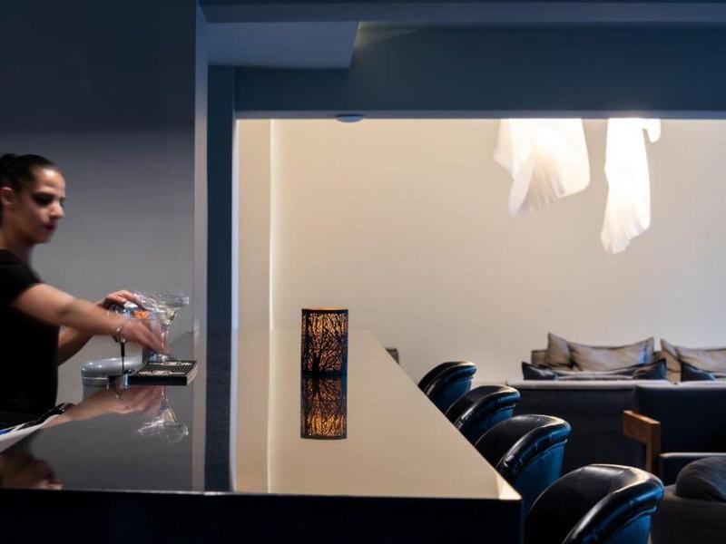 Bartender prepares drinks at a modern hotel bar with seating area.