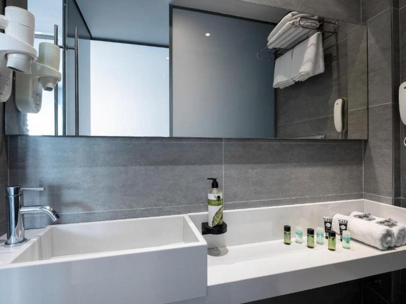 Modern bathroom with sink, mirror, towels, and toiletries.