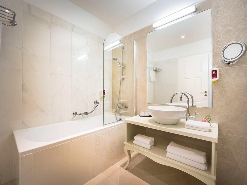 Nowoczesna łazienka z wanną, umywalką na blacie i dużym lustrem.