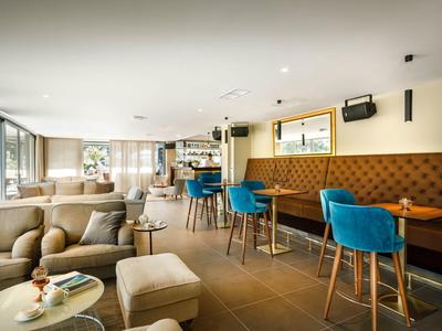 Modernes Café mit beiger Polstermöbeln, blauen Barhockern und großem Fenster für Tageslicht.