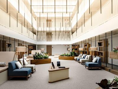 Ruime moderne lobby met zitgroepen, houten details en veel natuurlijk licht.