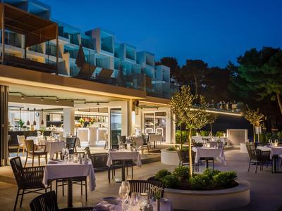 Hotelterras bij schemering met gedekte tafels en moderne architectuur.